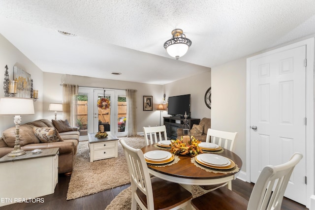 dining room with a textured ceiling and dark hardwood / wood-style floors