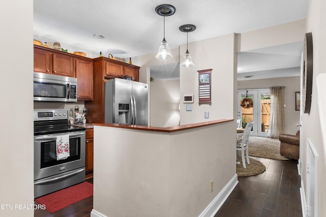 kitchen featuring hanging light fixtures, kitchen peninsula, stainless steel appliances, a textured ceiling, and dark hardwood / wood-style floors