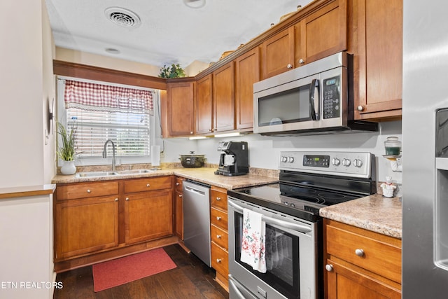 kitchen featuring light stone countertops, sink, dark wood-type flooring, and stainless steel appliances