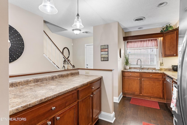 kitchen featuring a textured ceiling, dark hardwood / wood-style flooring, pendant lighting, and sink