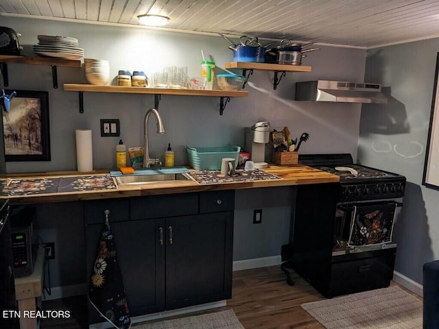 kitchen with black gas stove, wood ceiling, sink, wall chimney range hood, and hardwood / wood-style flooring