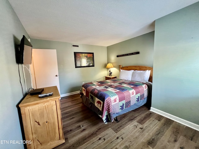 bedroom featuring a textured ceiling and dark wood-type flooring