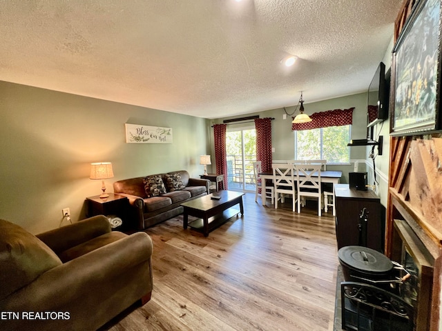 living room featuring light wood-type flooring, a textured ceiling, and a fireplace