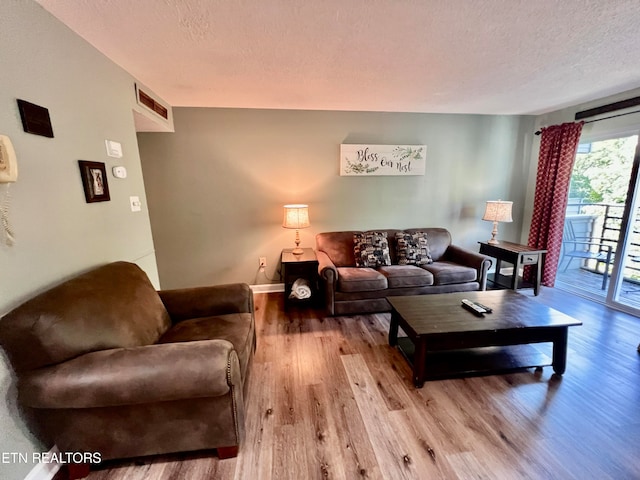 living room featuring light wood-type flooring and a textured ceiling