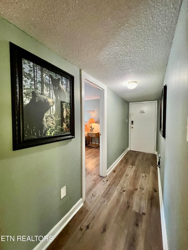 corridor with hardwood / wood-style flooring and a textured ceiling