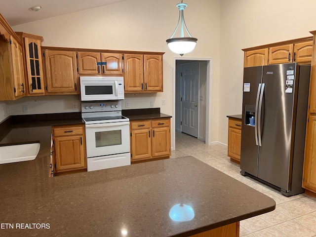 kitchen with light tile patterned floors, white appliances, vaulted ceiling, and sink