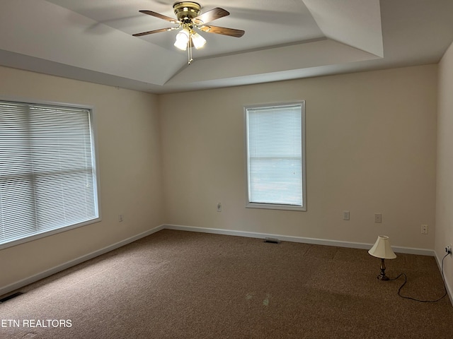 carpeted empty room featuring ceiling fan, a raised ceiling, and lofted ceiling