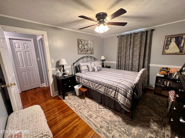 bedroom with a closet, a textured ceiling, dark hardwood / wood-style floors, crown molding, and ceiling fan