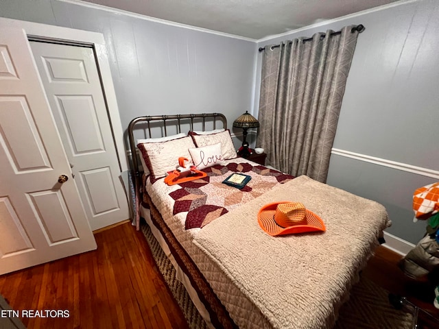 bedroom featuring a closet, dark wood-type flooring, and crown molding