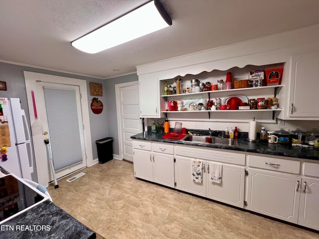 kitchen featuring sink, crown molding, white fridge, and white cabinetry