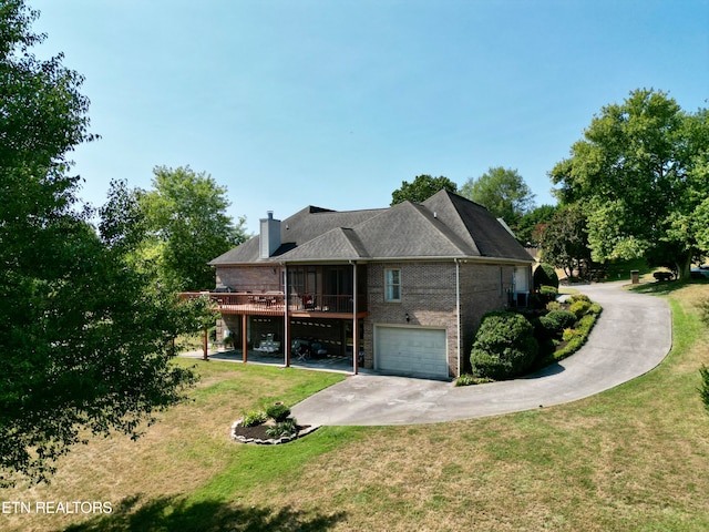 rear view of house with a garage, a deck, and a yard