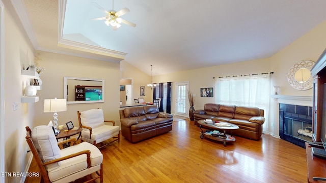 living room featuring ceiling fan with notable chandelier, a tiled fireplace, crown molding, wood-type flooring, and lofted ceiling