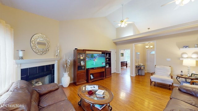 living room with a tile fireplace, ceiling fan, light hardwood / wood-style flooring, and high vaulted ceiling