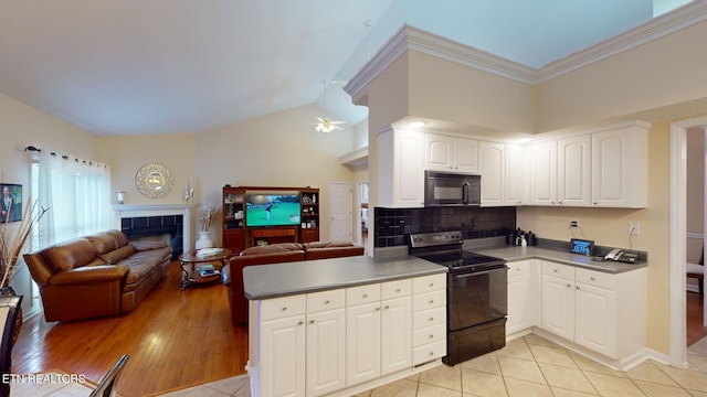 kitchen with a tiled fireplace, kitchen peninsula, white cabinetry, light hardwood / wood-style flooring, and black appliances