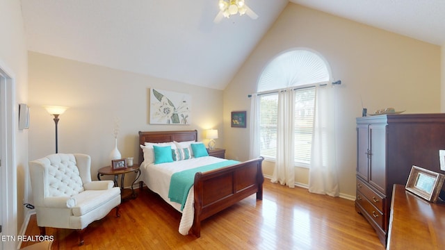 bedroom with light hardwood / wood-style floors, ceiling fan, and high vaulted ceiling