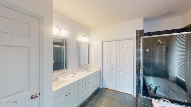 bathroom with a textured ceiling, independent shower and bath, and vanity