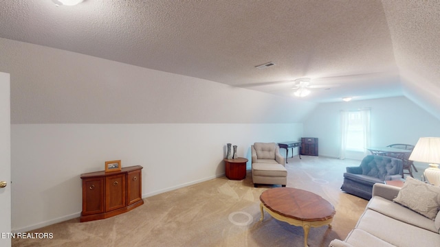 living area featuring ceiling fan, light colored carpet, a textured ceiling, and vaulted ceiling