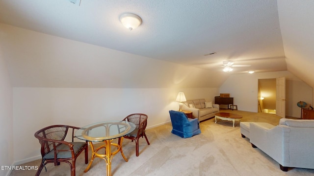 interior space featuring a textured ceiling, vaulted ceiling, ceiling fan, and light carpet