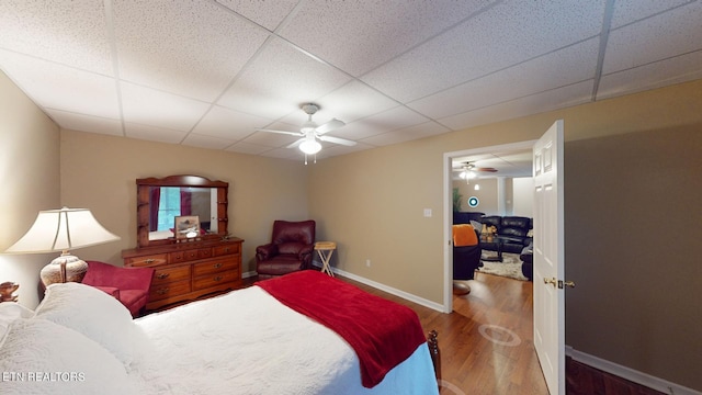 bedroom featuring a drop ceiling, hardwood / wood-style floors, and ceiling fan