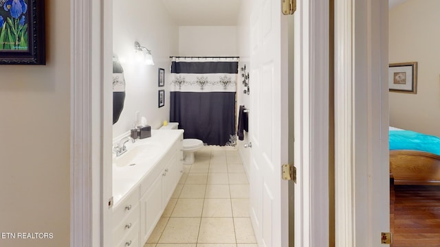 bathroom with tile patterned flooring, walk in shower, vanity, and toilet