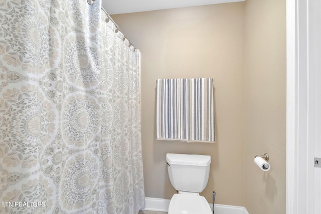 bathroom with toilet and a shower with shower curtain