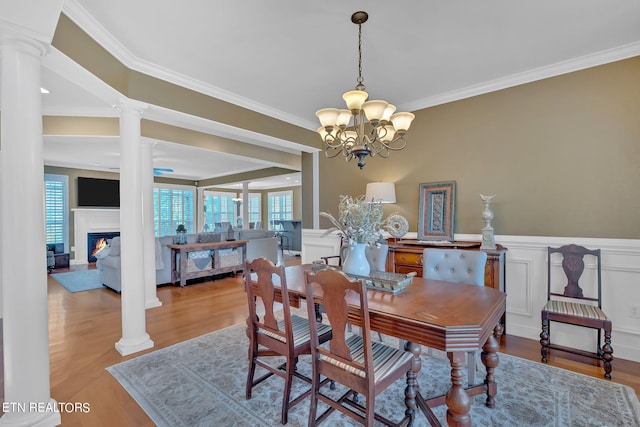 dining space with ornate columns, light hardwood / wood-style floors, and crown molding