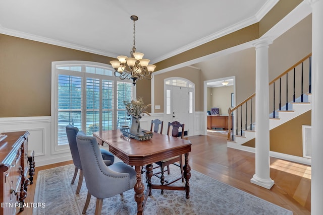 dining room featuring ornate columns, an inviting chandelier, crown molding, and hardwood / wood-style floors