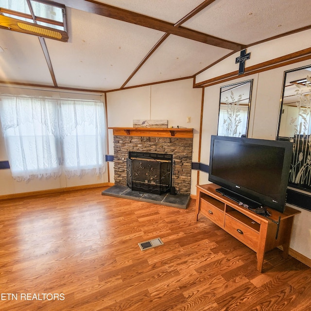 living room with vaulted ceiling with beams, a textured ceiling, hardwood / wood-style flooring, and a fireplace