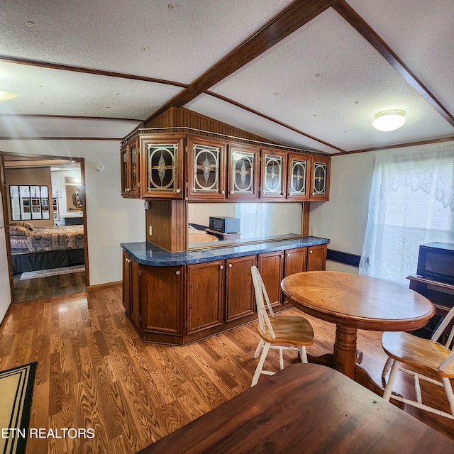 kitchen with a textured ceiling, vaulted ceiling with beams, and dark hardwood / wood-style flooring