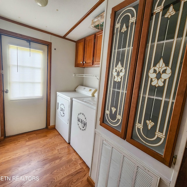 washroom featuring washing machine and clothes dryer, light hardwood / wood-style floors, cabinets, and ornamental molding