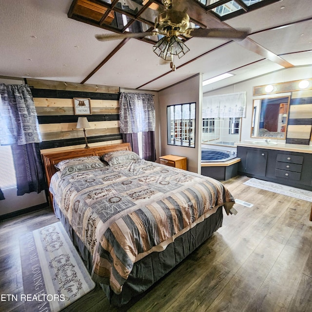 bedroom with hardwood / wood-style flooring, sink, vaulted ceiling, and a textured ceiling