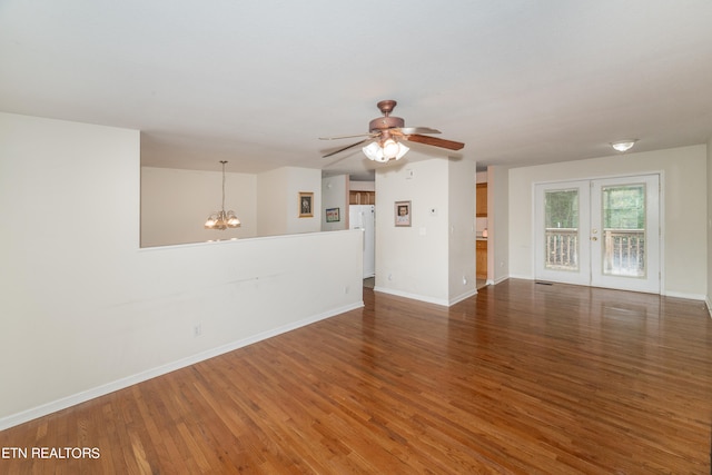 empty room featuring ceiling fan with notable chandelier and dark wood-type flooring