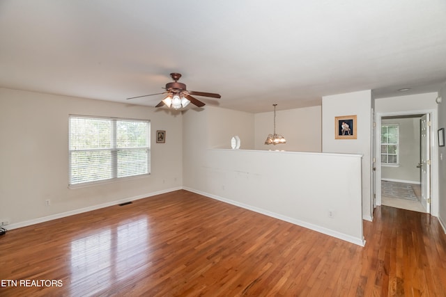 unfurnished room featuring wood-type flooring and ceiling fan with notable chandelier