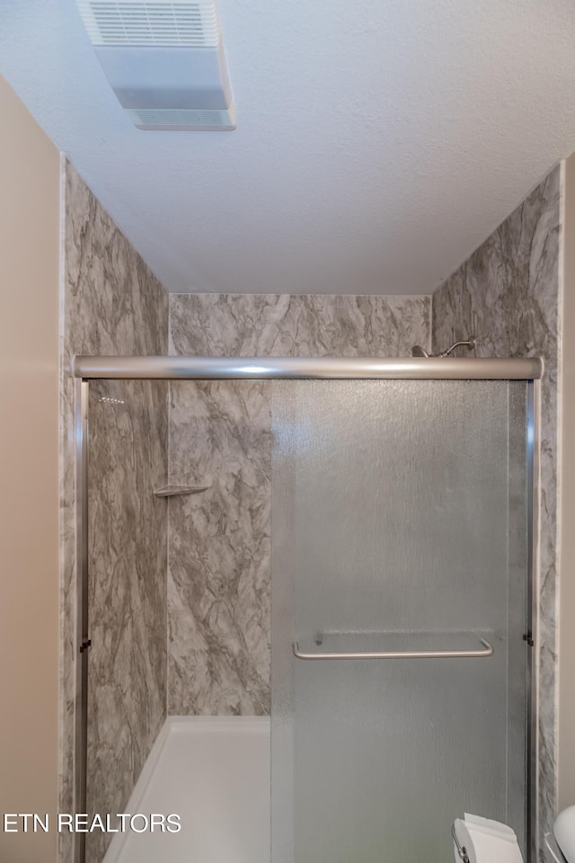 bathroom with a shower with shower door and toilet