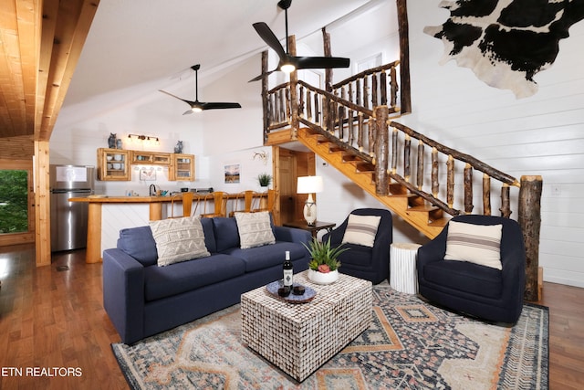 living room featuring wood walls, dark hardwood / wood-style flooring, ceiling fan, and high vaulted ceiling