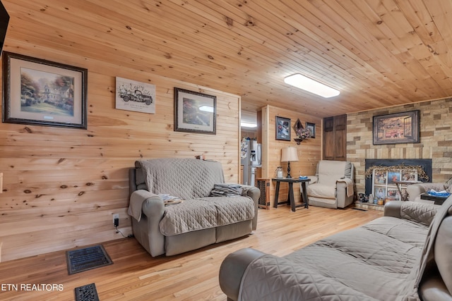 living room featuring wooden walls, light hardwood / wood-style flooring, and a fireplace