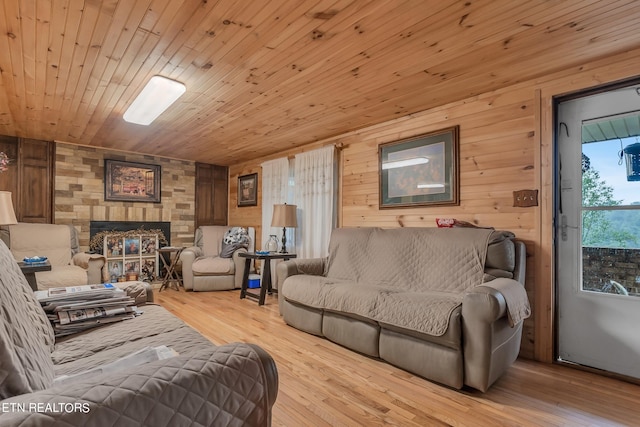 living room featuring wooden walls, light wood-type flooring, a fireplace, and wooden ceiling