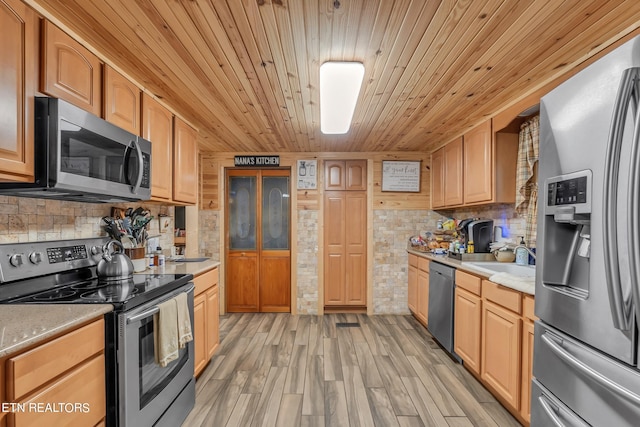 kitchen featuring appliances with stainless steel finishes, light wood-type flooring, sink, and tasteful backsplash