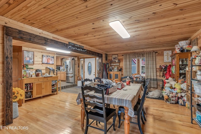 dining room with light wood-type flooring, wood walls, and wooden ceiling