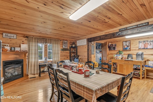 dining area featuring light hardwood / wood-style flooring, wooden walls, and wooden ceiling