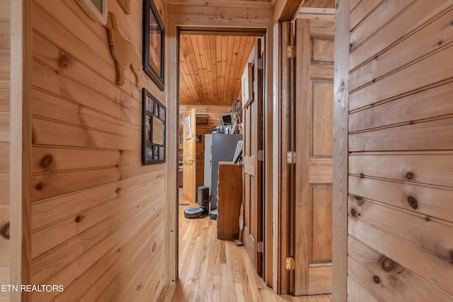 hall with wood ceiling, wooden walls, and light hardwood / wood-style floors