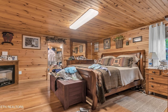 bedroom featuring wooden ceiling, light hardwood / wood-style floors, and wooden walls