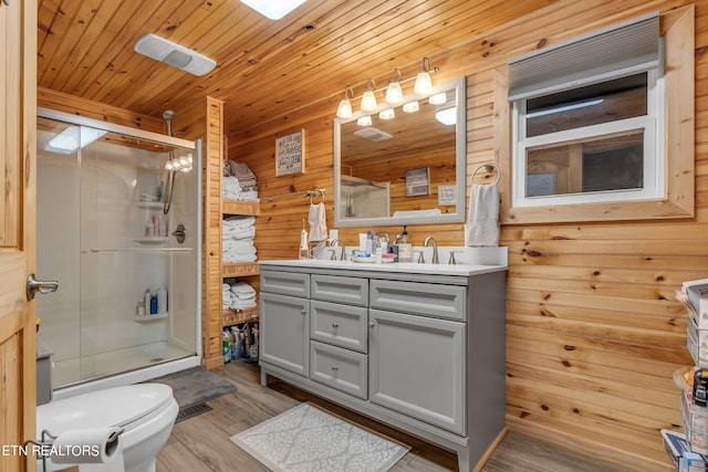 bathroom featuring wood-type flooring, wooden walls, a shower with shower door, vanity, and toilet