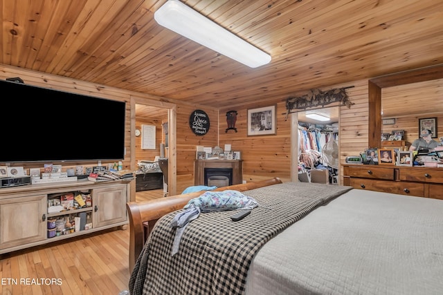 bedroom featuring wooden walls, wooden ceiling, and light wood-type flooring