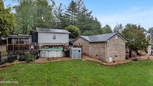 rear view of house with a lawn, a covered pool, a sunroom, and a shed