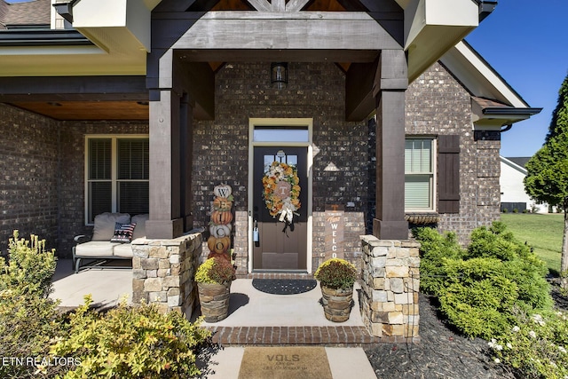 view of exterior entry featuring covered porch and brick siding