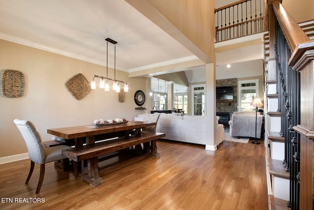 dining space with wood-type flooring, a fireplace, and crown molding