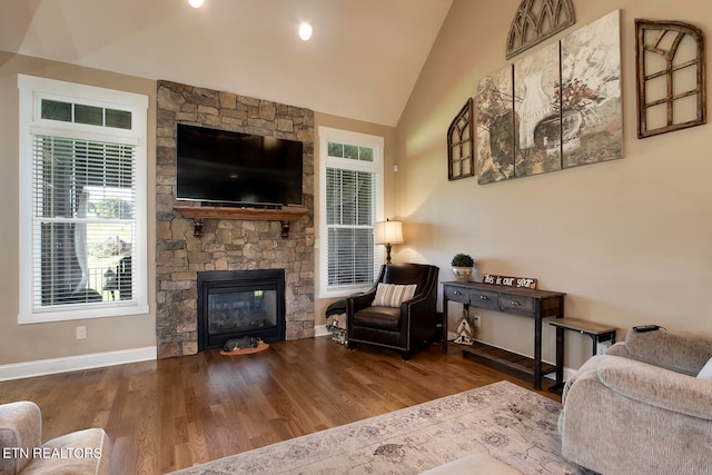 living room with lofted ceiling, a stone fireplace, and hardwood / wood-style floors