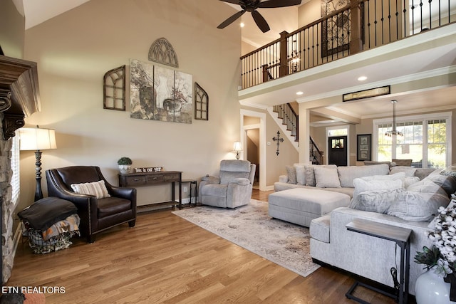 living room featuring crown molding, a ceiling fan, stairway, wood finished floors, and baseboards