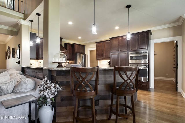 kitchen with dark brown cabinets, ornamental molding, and appliances with stainless steel finishes
